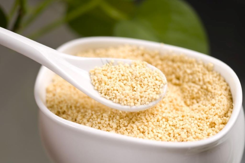 Close-up of lecithin granules beside a jar of creamy homemade emulsion