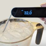 A digital reef tank thermometer probe being placed into an ice bath slurry for calibration
