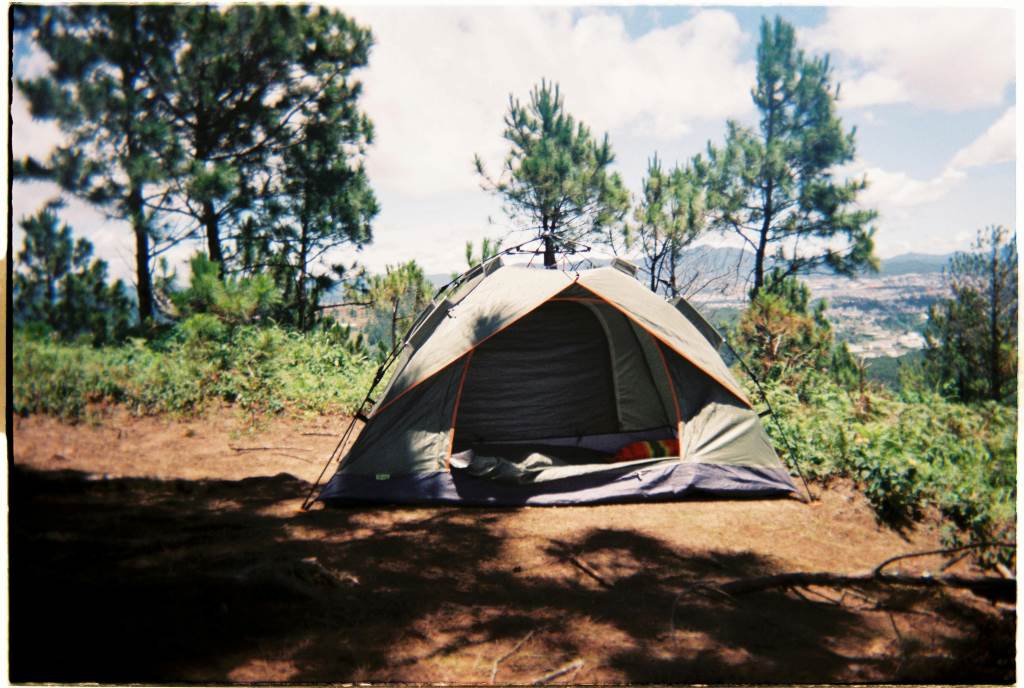 Outdoor scene with Faxco 10ft rope securing a tent in a forested campsite under soft sunlight.