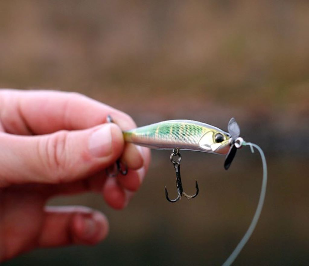 Close-up of spybait lure with treble hooks suspended in water column for bass fishing