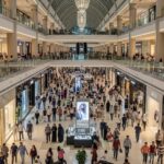 Crowded interior view of Dubai Mall showing multiple floors filled with shoppers and luxury retail stores