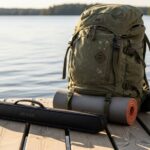 Compact collapsible fishing rod in a carrying case next to a travel backpack