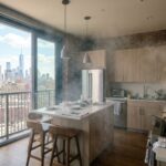 Kitchen filled with smoke with windows open to a city view.
