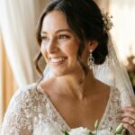 Bride wearing sparkling drop earrings against a lace wedding dress.