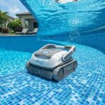 Cordless robotic pool cleaner scrubbing a clear residential swimming pool.